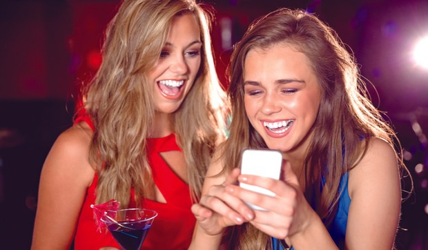 652816_stockphotoprettyfriendslookingatsmartphonetogetheratthenightclub244299718
