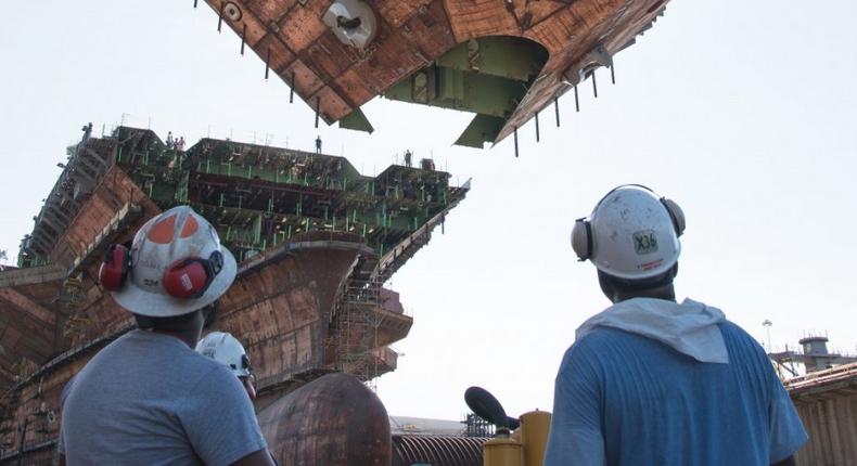 Shipyard workers watch as the upper bow unit of the future aircraft carrier USS John F. Kennedy (CVN 79) is fitted to the primary structure of the ship, July 10, 2019, at Huntington Ingalls Industries Newport News Shipbuilding.