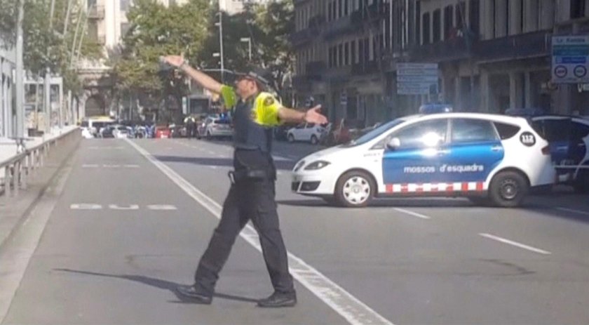 A still image from video shows a police officer gesturing while walking across a road, after a van c