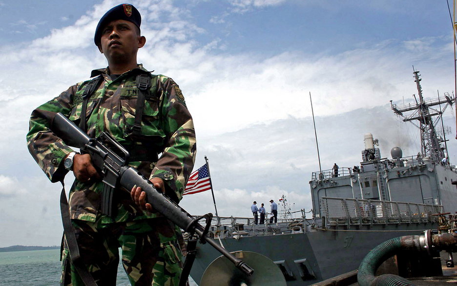 Żołnierz indonezyjskiej marynarki wojennej obok amerykańskiego okrętu USS Reuben James w cieśninie Malakka