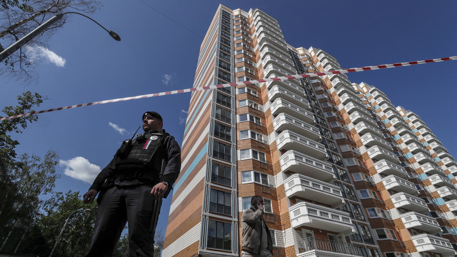 Rosyjski policjant stoi na straży w pobliżu uszkodzonego budynku mieszkalnego po ataku drona w Moskwie