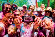 People taking a selfie together in group during a Holi celebration party in the outdoor with happiness expressions and covered with vivid colors.