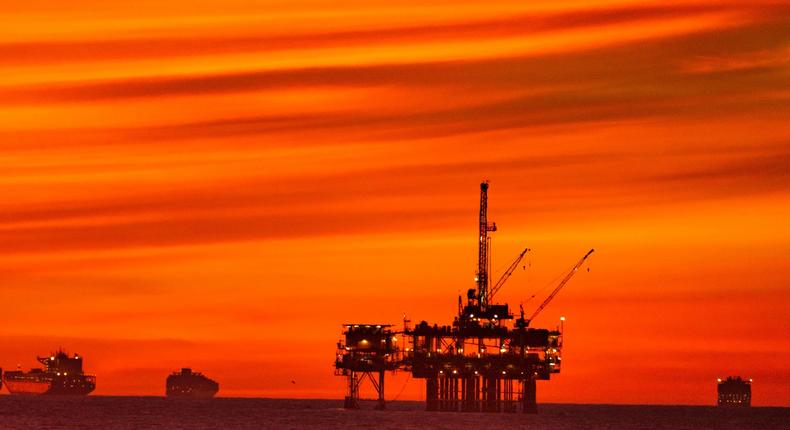 The sun sets over container ships and oil platforms off the coast of Huntington Beach.