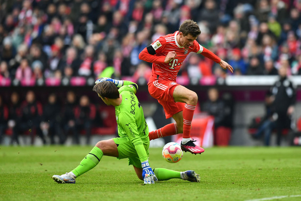 epa10460997 Munich's Thomas Mueller (R) scores the opening goal against Bochumâ€™s goalkeeper Manuel Riemann (L) during the German Bundesliga soccer match between FC Bayern Munich and VfL Bochum in Munich, Germany, 11 February 2023. EPA/ANNA SZILAGYI CONDITIONS - ATTENTION: The DFL regulations prohibit any use of photographs as image sequences and/or quasi-video. Dostawca: PAP/EPA.