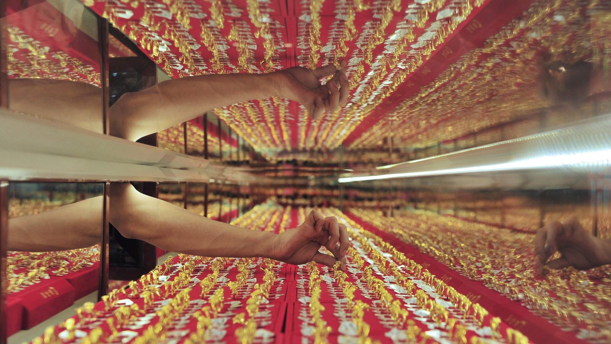 A shop attendant picks a gold ring for a customer at a store in Shenyang, China's Liaoning province