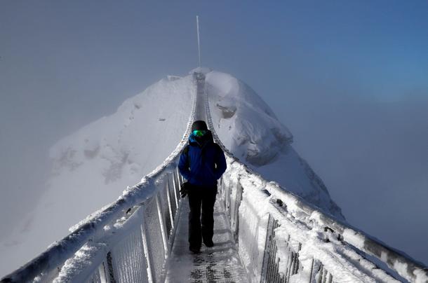 A snowboarder walks on the Peak Walk bridge at Glacier 3000 in Les Diablerets