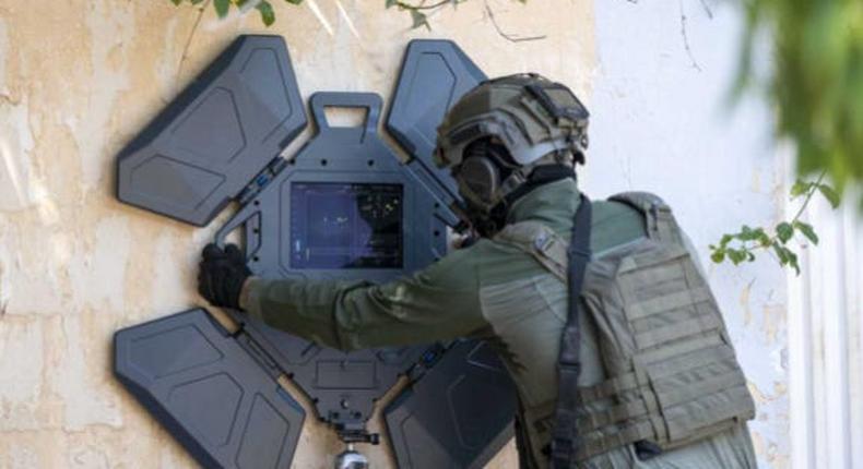 A person using Camero-Tech's Xaver 1000 system to see objects behind a wall.