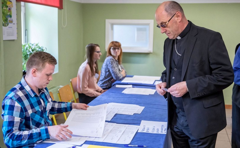Prymas Polski abp Wojciech Polak (P) głosuje w lokalu wyborczym w budynku Szkoły Podstawowej nr 1 im. Zjazdu Gnieźnieńskiego w Gnieźnie