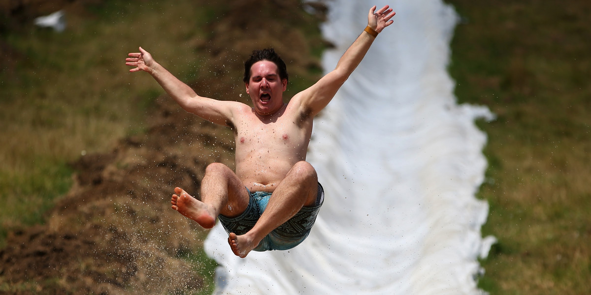 People enjoy the muddy thrills and spills on a waterslide dug into a hillside in Waimauku on February 23, 2013 in Auckland, New Zealand.
