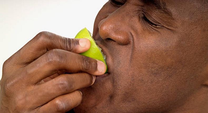 Close-up of a man biting into a lemon half