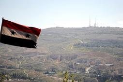A Syrian national flag flutters as Qasioun mountain is seen in the background from Damascus