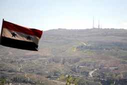 A Syrian national flag flutters as Qasioun mountain is seen in the background from Damascus