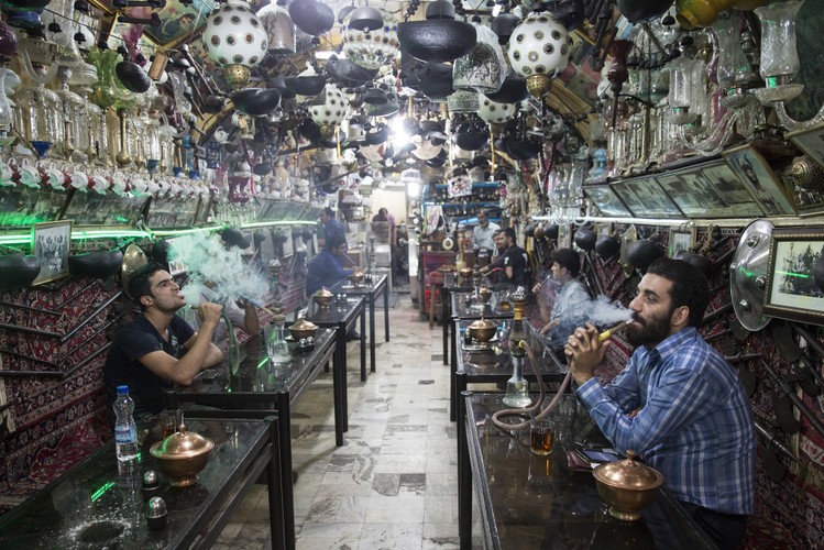 Choć nowoczesność nieubłaganie wkracza do prawie wszystkich sfer życia Irańczyków, to wciąż istnieje wiele miejsc, gdzie udało się zachować tradycję. Na zdjęciu klienci tradycyjnej herbaciarni Haj Mirza na jednym z bazarów w Isfahanie palą shishę, 27.08.2015, Iran.