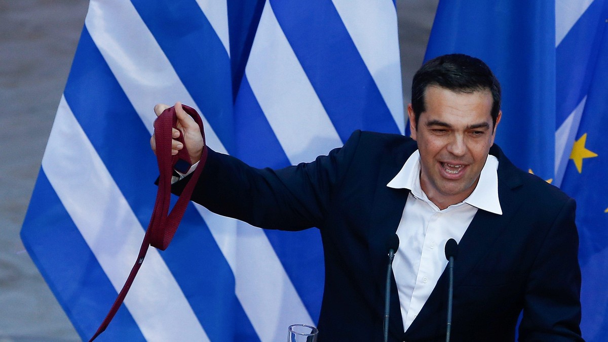 Greek Prime Minister Alexis Tsipras, holds his tie, as he speaks at the parliamentary group of Syriz