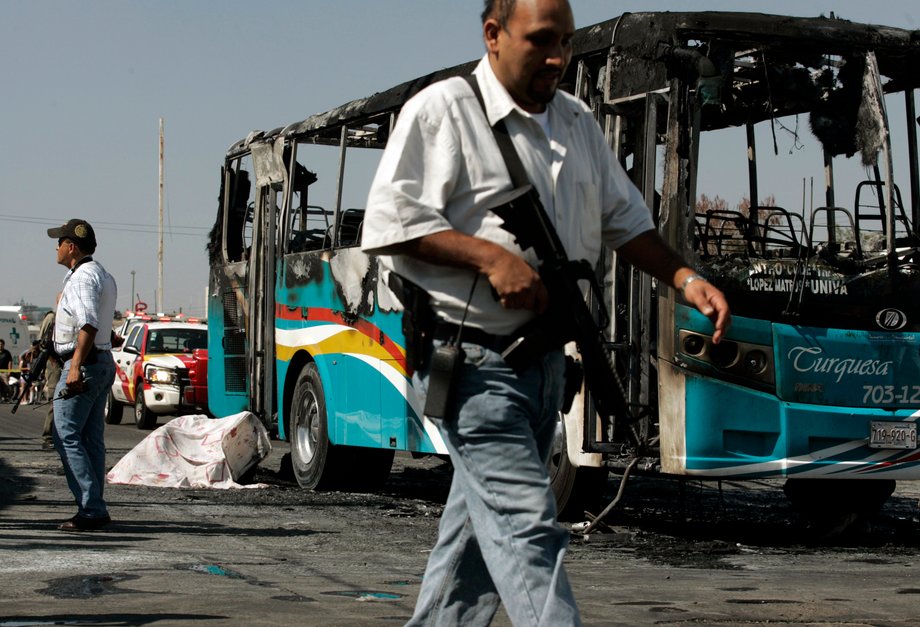 Police officers near the covered body of a person who died after a bus was set on fire in Guadalajara in 2012. Gunmen torched vehicles and blocked roads in Guadalajara during a military operation to arrest two Jalisco New Generation cartel leaders.