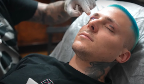 Mateusz Trąbka w trakcie robienia tatuażu na powiekach 