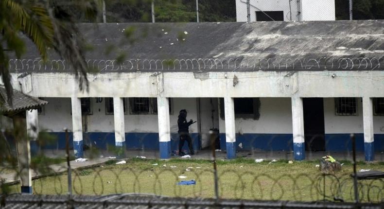 A policeman patrols outside the Stage II Male Juvenile Detention Center in San Jose Pinula, before an operation to rescue four hostages held by inmates inside the prison on March 20, 2017