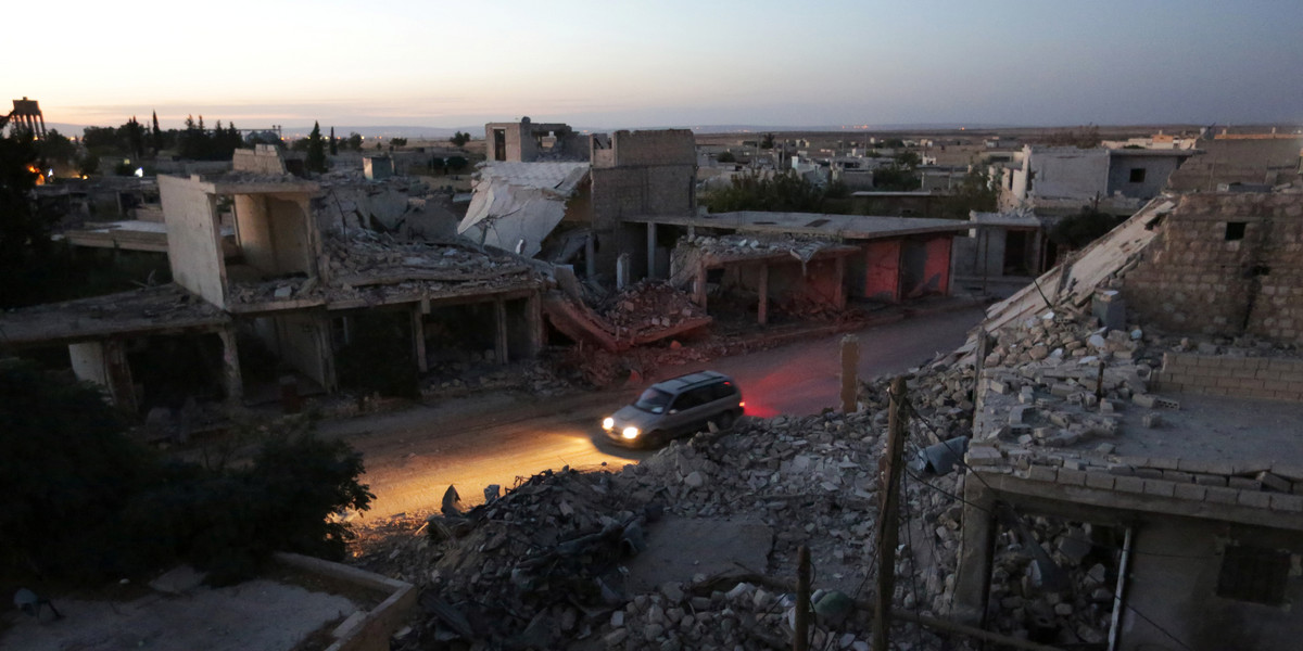 A vehicle drives past damaged buildings in the northern Syrian rebel-controlled town of al-Rai, in Aleppo Governorate, Syria, September 26, 2016.