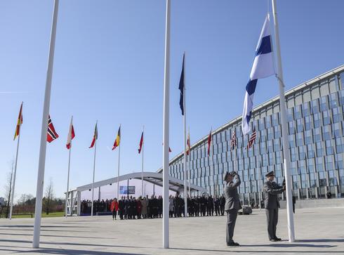 Flaga Finlandii jest podnoszona na maszt przed siedzibą NATO / źródło: PAP