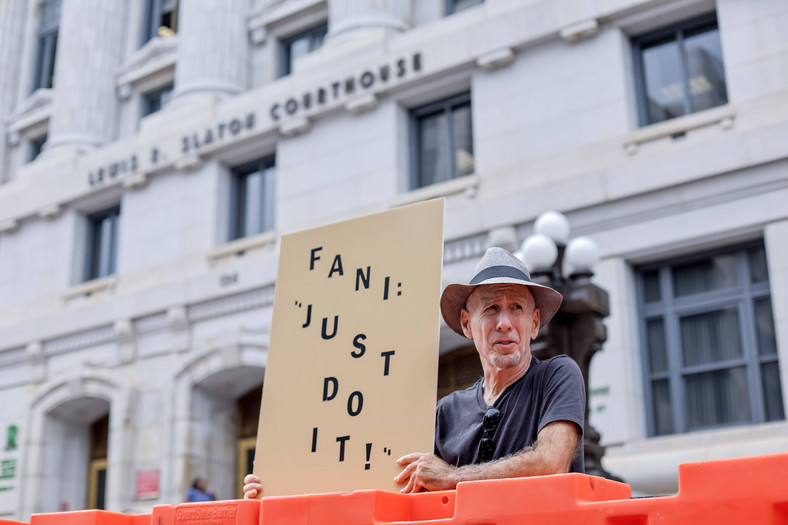 Samotny protestujący trzyma znak przed budynkiem sądu hrabstwa Fulton, Atlanta, Georgia, USA, 7 sierpnia 2023 r.