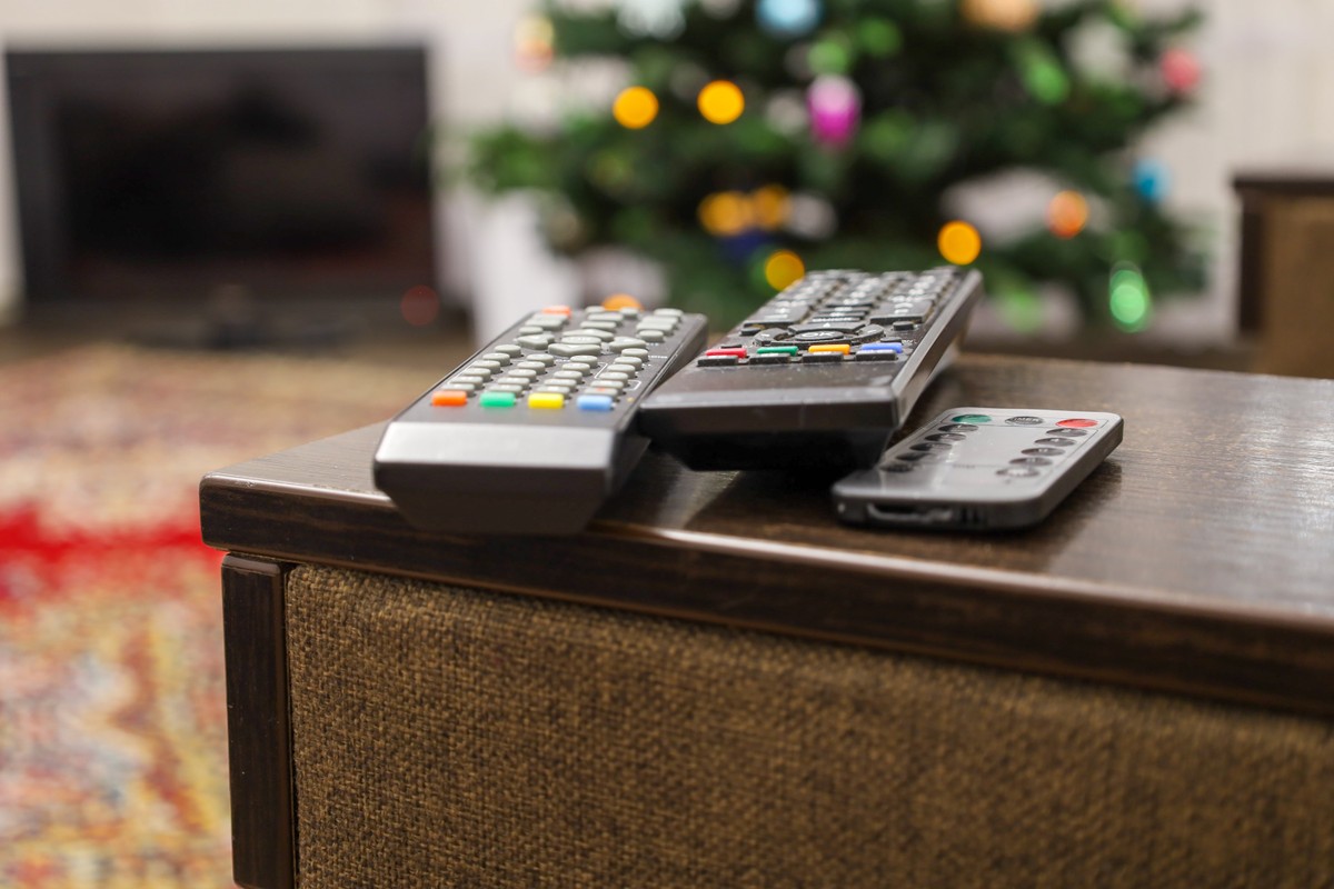 Several,Remote,Controls,Lie,On,The,Wooden,Armrest,Of,An