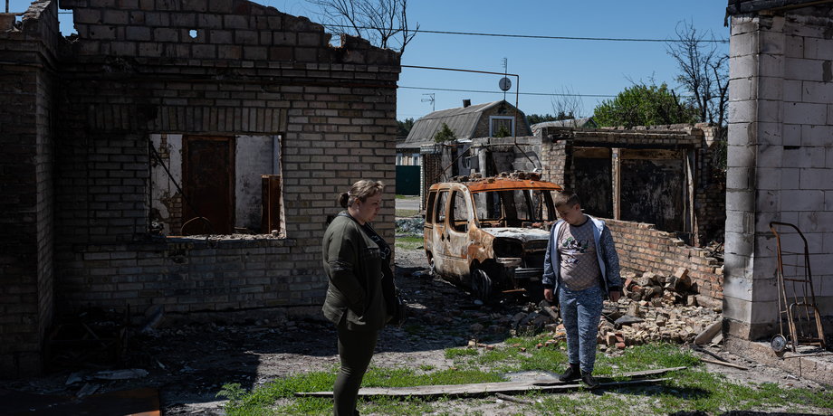 Rodzina przed zniszczonym domem w Moszczunie w Ukrainie