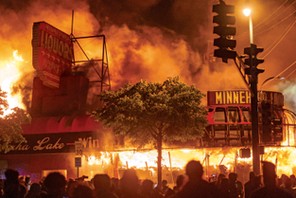 Protestujący po śmierci George'a Floyda gromadzą się pod płonącym sklepem z alkoholem w Minneapolis. Fot. Katem Yucel/AFP/East News