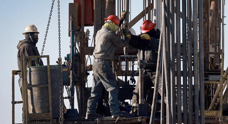 Workers place pipe into the ground on an oil drilling rig set up in the Permian Basin oil field on March 12, 2022 in Midland, Texas.