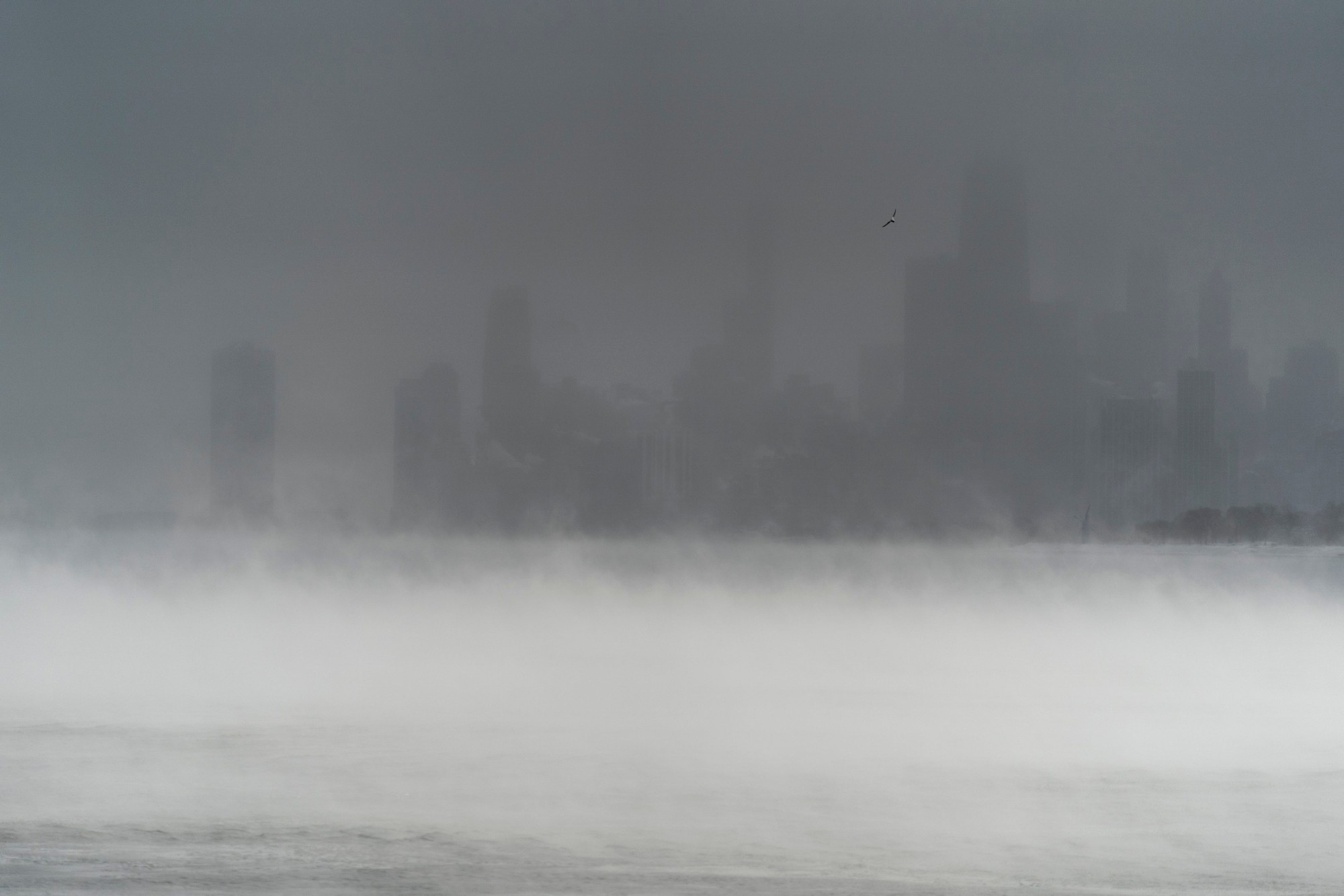 Panorámu centra Chicaga zakrýva fúkajúci sneh a para stúpajúca z jazera Michigan, piatok 23 decembra 2022 v Chicagu.