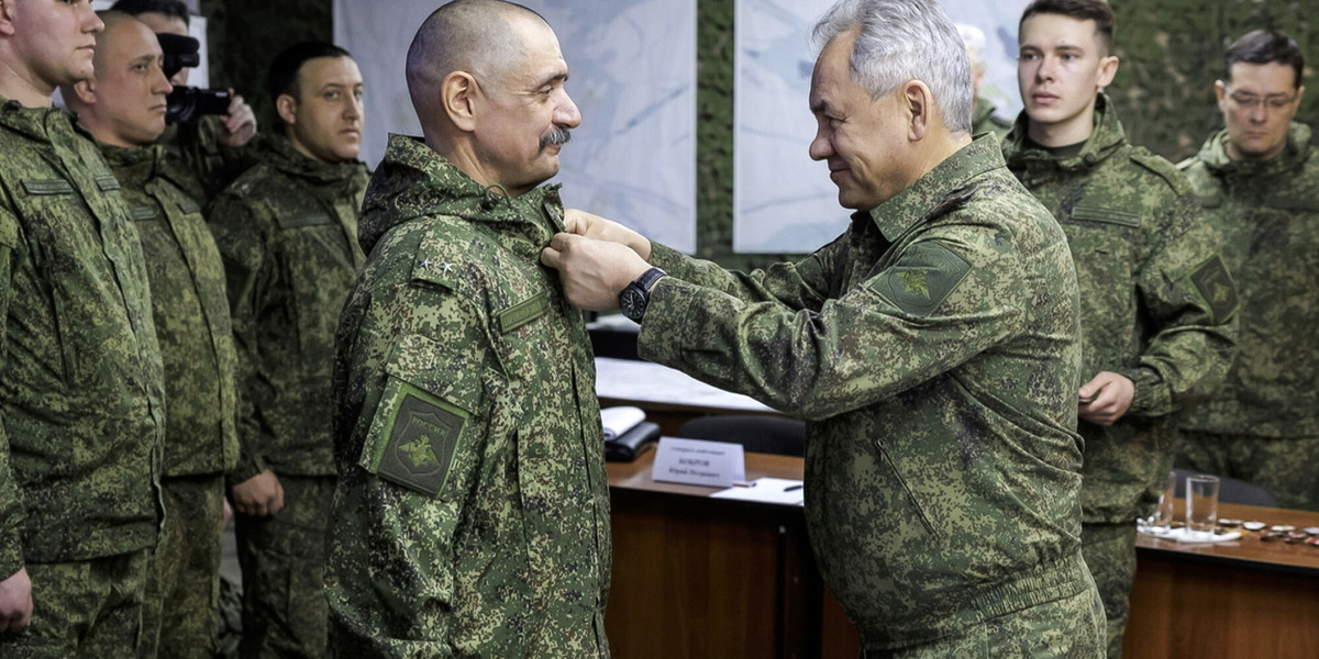 Minister obrony Rosji Siergiej Szojgu nagradza oficera podczas inspekcji wojsk.
