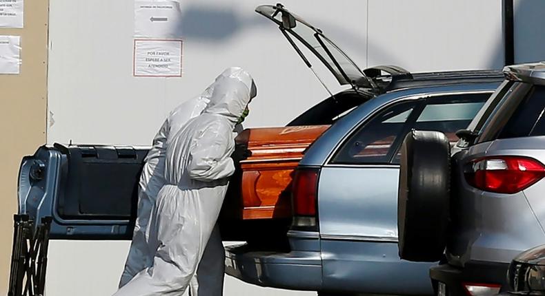 Employees of a Santiago funeral parlour load a coffin of a person who died of COVID-19 into a relative's vehicle outside the San Jose Hospital -- the Chilean capital has borne the brunt of the country's outbreak