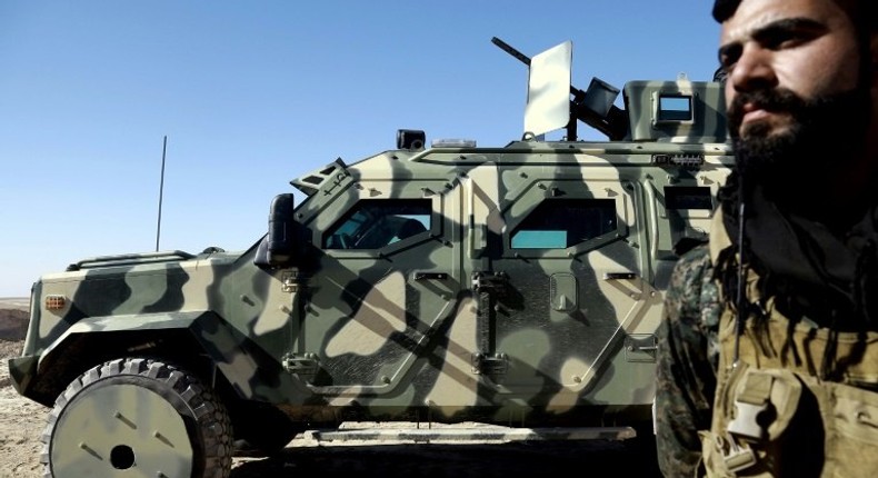 A fighter from the Syrian Democratic Forces, stands next to a military vehicle supplied by the US-led coalition, as advance towards Syria's Raqa on February 3, 2017