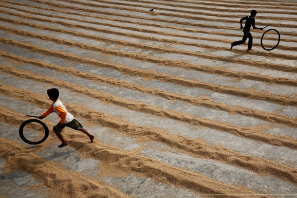 Children play with bicycle tires at a rice-processing mill in Muktarpur