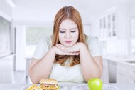 Confused woman choose apple or hamburger