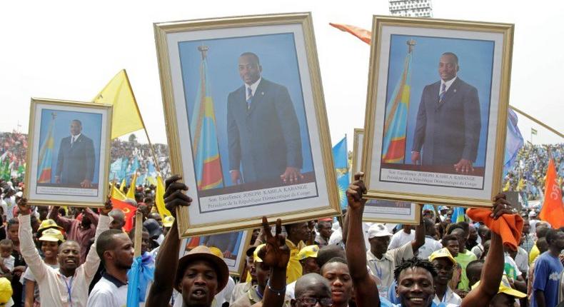 Supporters of Congolese President Kabila carry his portrait photographs during a pro-government rally in Kinshasa