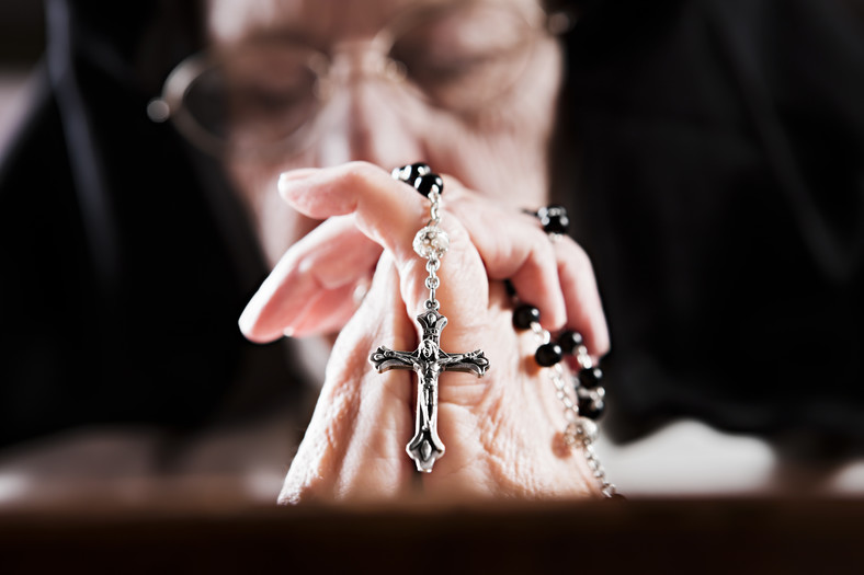 Modląca się zakonnica, ściska w dłoni różaniec