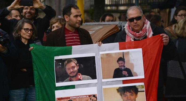 People hold an Italian flag bearing photos of murdered student Giulio Regeni during a protest in Rome on February 25, 2016