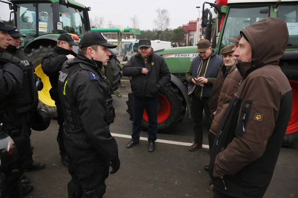 Policjanci kontrolują dokumenty rolników na miejscu rolniczej blokady na wjeździe do Warszawy od strony wschodniej