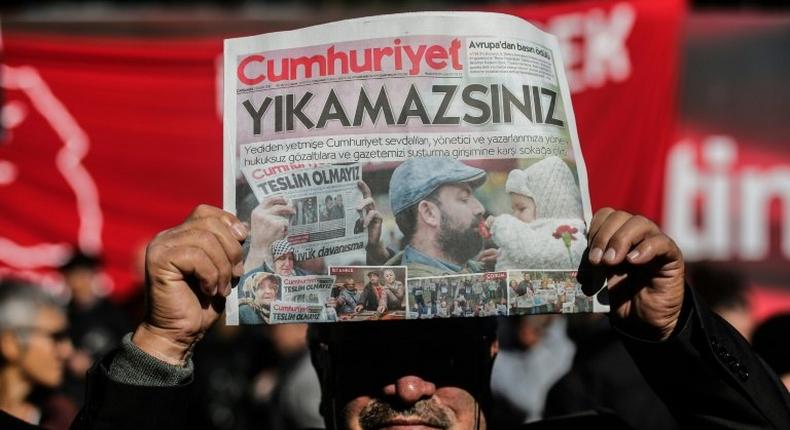 A protester holds a copy of the latest edition of the Turkish daily newspaper Cumhuriyet during a demonstration outside the newspaper's headquarters in Istanbul on November 2,2016