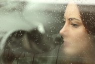 Sad woman looking through a car window