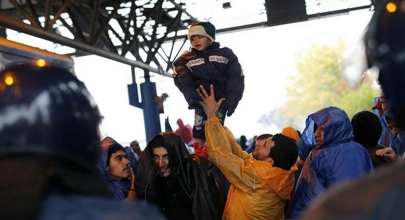A migrant lifts a child as they wait to cross the border with Slovenia in Trnovec, Croatia October 19, 2015.   REUTERS/Antonio Bronic
