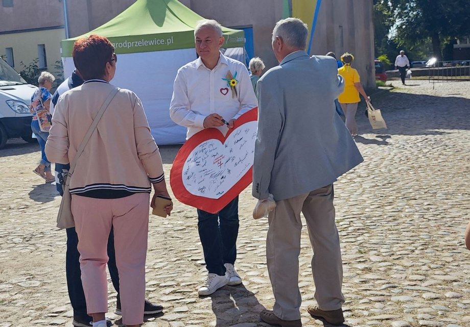 Grzegorz Napieralski z wielkim logo KO podczas rozmów z dożynkowiczami