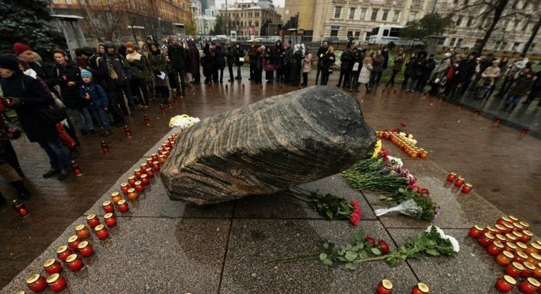 People place candles and flowers at the memorial for the victims of the Soviet-era political repression, the Solovky Stone monument, on Lubyanka Square in Moscow on October 29, 2016