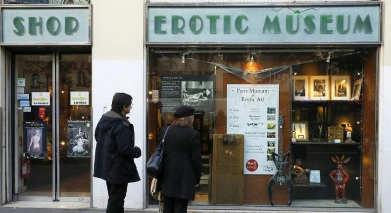 Two people stand in front of the the Erotic Museum of Paris on November 2, 2016 prior to the auction sale of the collection on November 6 and the closure of the museum