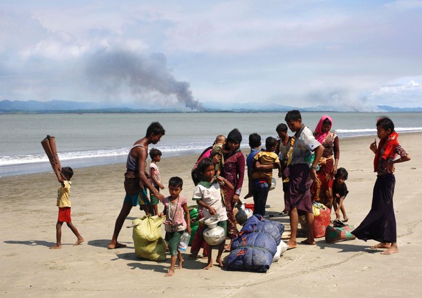 Smoke is seen on Myanmar's side of border as Rohingya refugees collect their belongings on a shore a