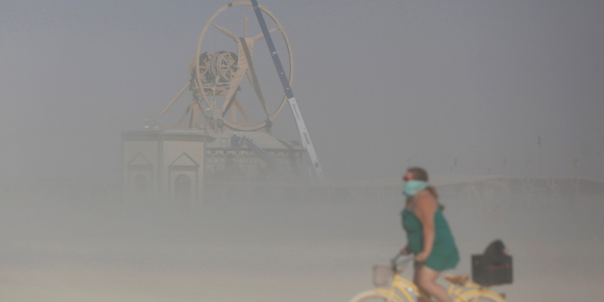 A Burner bicycling through a dust storm during Burning Man 2016.