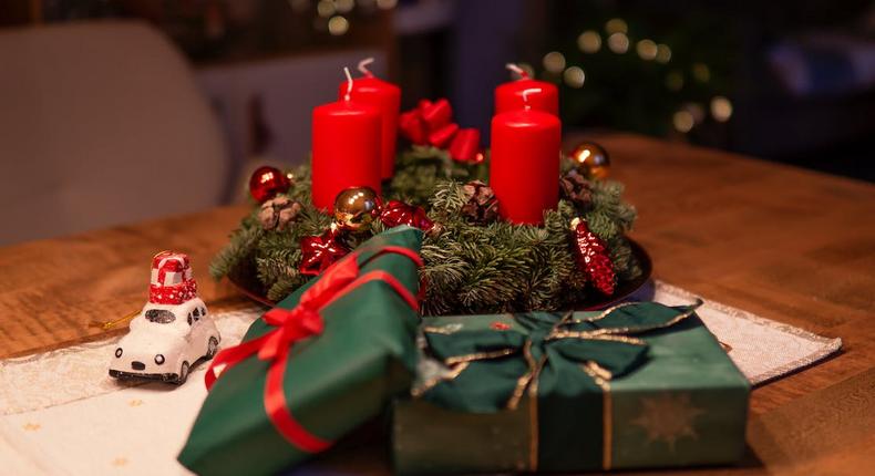 Unlighted red advent candles on a table beside green gift boxes [Credit: Alex Fu]