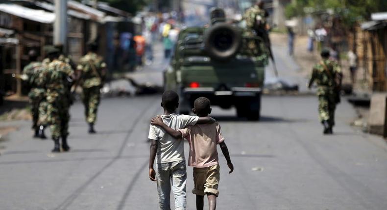 Boys walk behind patrolling soldiers in Bujumbura, Burundi, May 15, 2015. REUTERS/Goran Tomasevic/Files