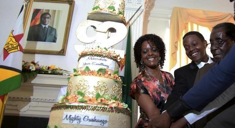 Zimbabwean President Robert Mugabe (R) is helped by his wife Grace (L) and son Chatunga (C) to cut a cake to celebrate his 92nd birthday at State House in Harare, February 22, 2016. Mugabe turned 92 on Sunday. REUTERS/Philimon Bulawayo