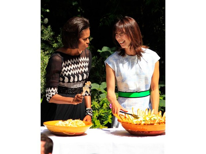 Nawet podczas barbecie w ogrodzie najlepiej wyglądać stylowo. Michelle Obama w czarno-białej sukni serwuje potrawy gościom wraz z Samantą Cameron